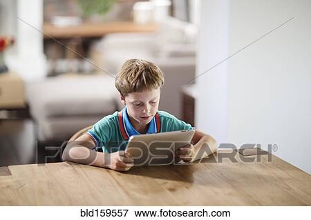 Stock Photo - Caucasian boy using digital tablet at table. Fotosearch