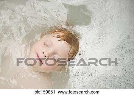 Stock Image - Caucasian boy with eyes closed in bubble bath. Fotosearch