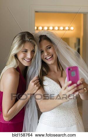 Caucasian bride and bridesmaid taking selfie View Large Photo Image Picture - Caucasian bride and bridesmaid taking selfie. Fotosearch