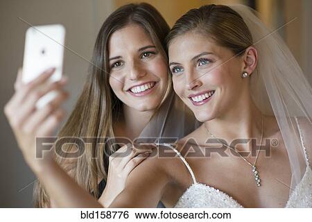 Stock Photograph - Caucasian bride and bridesmaid taking selfie. Fotosearch