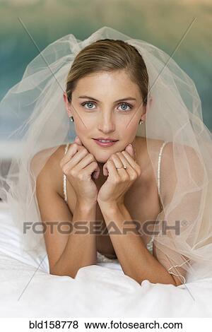 Stock Photo - Caucasian bride in wedding veil leaning on elbows. Fotosearch