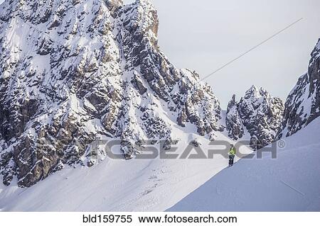 Stock Photography - Caucasian climber standing on snowy mountain slope. Fotosearch