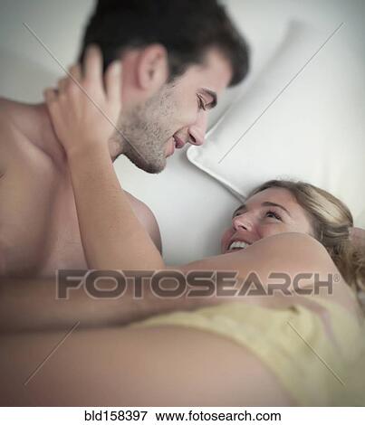 Stock Photo - Caucasian couple cuddling in bed. Fotosearch
