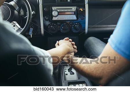 Stock Image - Caucasian couple holding hands in car. Fotosearch