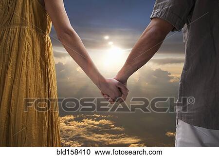 Caucasian couple holding hands in dramatic sunset sky View Large Photo Image Stock Image - Caucasian couple holding hands in dramatic sunset sky. Fotosearch