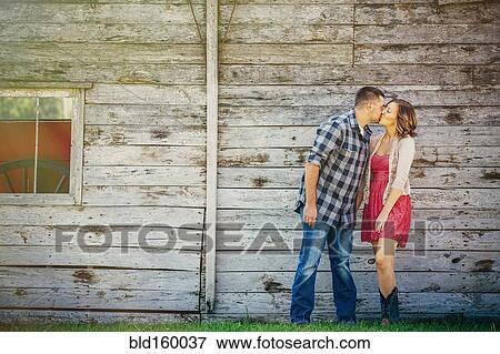 Stock Photo - Caucasian couple kissing near wooden building. Fotosearch