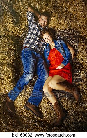 Stock Image - Caucasian couple laying on haystacks. Fotosearch