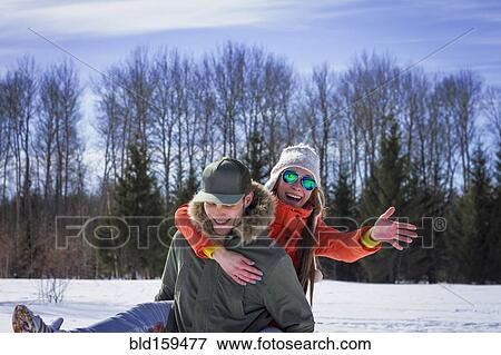 Stock Photo - Caucasian couple playing in snowy field. Fotosearch