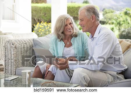 Caucasian couple using laptop on sofa outdoors View Large Photo Image Stock Image - Caucasian couple using laptop on sofa outdoors. Fotosearch