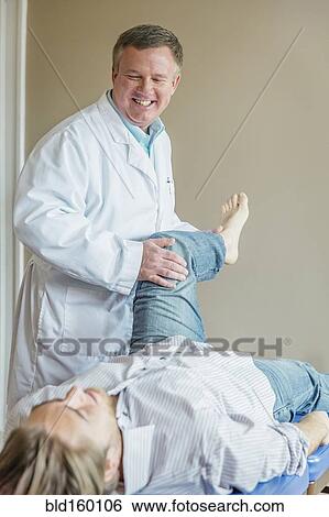 Caucasian doctor adjusting leg of patient View Large Photo Image Stock Photograph - Caucasian doctor adjusting leg of patient. Fotosearch