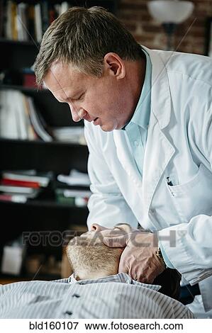 Caucasian doctor adjusting neck of patient View Large Photo Image Stock Photo - Caucasian doctor adjusting neck of patient. Fotosearch