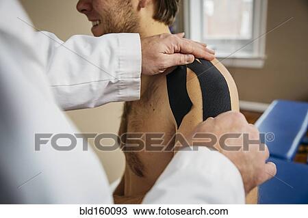 Caucasian doctor applying tape to shoulder of patient View Large Photo Image Stock Image - Caucasian doctor applying tape to shoulder of patient. Fotosearch