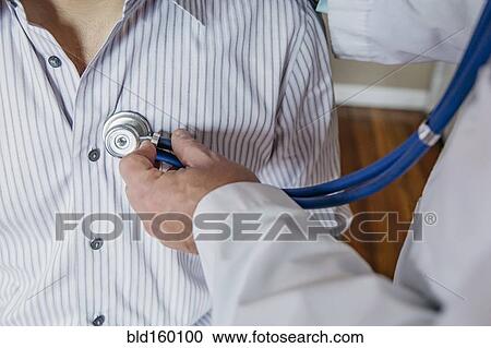 Stock Image - Caucasian doctor listening to heartbeat of patient. Fotosearch