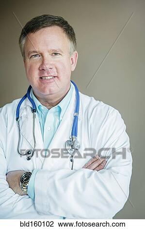 Stock Image - Caucasian doctor standing with arms crossed. Fotosearch