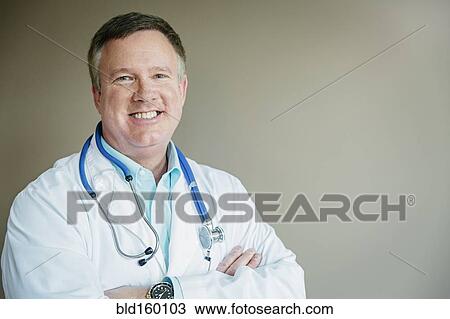 Stock Image - Caucasian doctor standing with arms crossed. Fotosearch