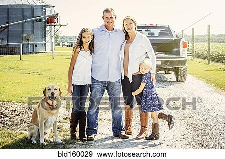 Stock Photo - Caucasian family and dog standing on farm road. Fotosearch