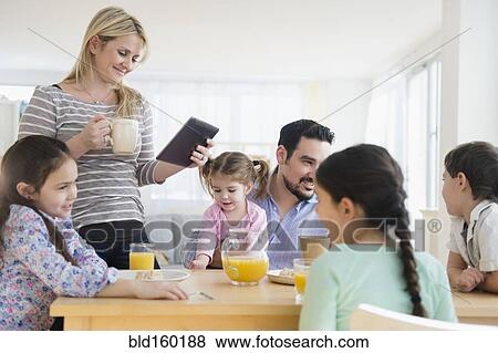Stock Photo - Caucasian family eating breakfast at table. Fotosearch