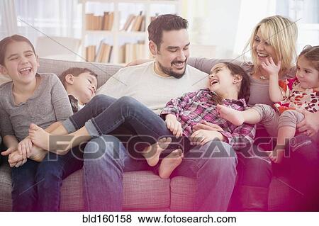 Stock Photo - Caucasian family playing on sofa. Fotosearch