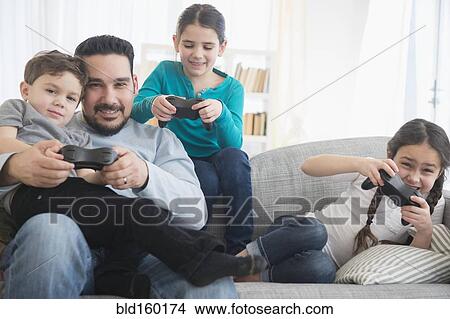 Caucasian father and children playing video games on sofa View Large Photo Image Picture - Caucasian father and children playing video games on sofa. Fotosearch
