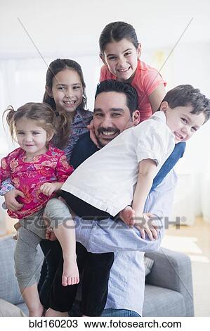 Stock Image - Caucasian father and children relaxing in living room. Fotosearch