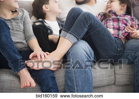 Stock Photo - Caucasian father and children relaxing on sofa. Fotosearch