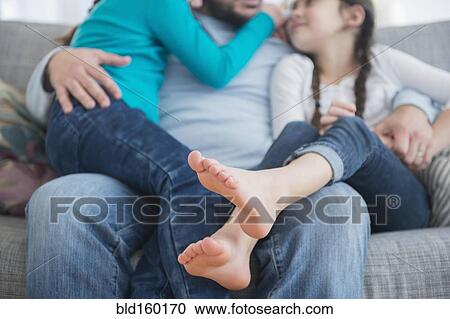 Caucasian father and daughters hugging on sofa View Large Photo Image Stock Image - Caucasian father and daughters hugging on sofa. Fotosearch