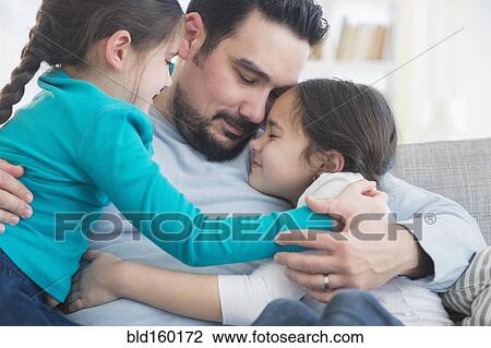 Caucasian father and daughters hugging on sofa View Large Photo Image Stock Image - Caucasian father and daughters hugging on sofa. Fotosearch