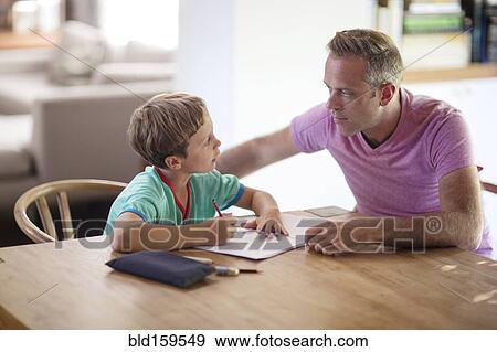 Stock Photo - Caucasian father and son drawing at table. Fotosearch