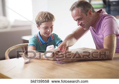 Stock Photo - Caucasian father and son examining model airplane at table. Fotosearch