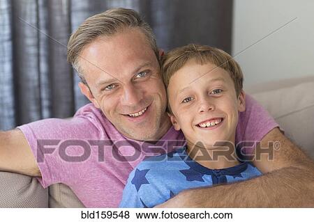 Stock Photo - Caucasian father and son hugging on sofa. Fotosearch