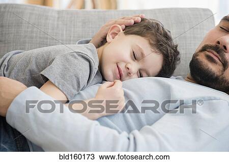 Stock Image - Caucasian father and son napping on sofa. Fotosearch
