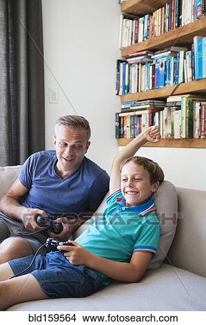 Caucasian father and son playing video games on sofa View Large Photo Image Picture - Caucasian father and son playing video games on sofa. Fotosearch