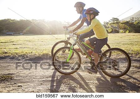 Caucasian father and son riding bicycles on dirt path View Large Photo Image Stock Photo - Caucasian father and son riding bicycles on dirt path. Fotosearch