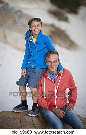 Stock Image - Caucasian father and son smiling on beach. Fotosearch