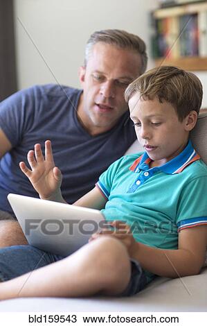 Caucasian father and son using digital tablet on sofa View Large Photo Image Stock Image - Caucasian father and son using digital tablet on sofa. Fotosearch
