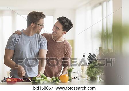 Stock Photo - Caucasian gay couple cooking in kitchen. Fotosearch
