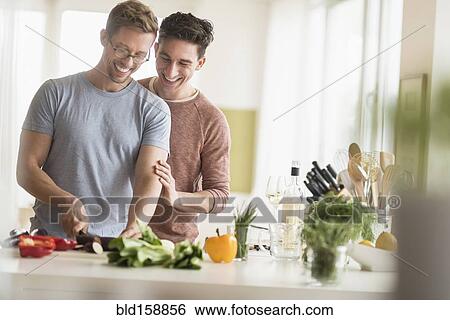 Stock Photograph - Caucasian gay couple cooking in kitchen. Fotosearch