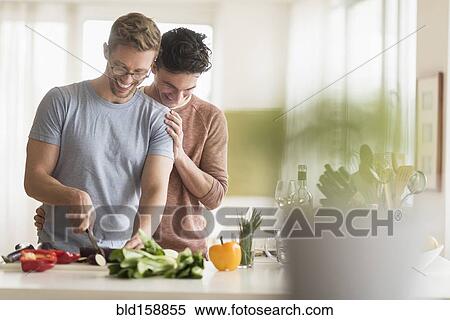 Stock Photography - Caucasian gay couple cooking in kitchen. Fotosearch