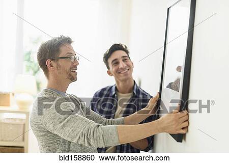 Caucasian gay couple hanging picture on wall View Large Photo Image Stock Image - Caucasian gay couple hanging picture on wall. Fotosearch