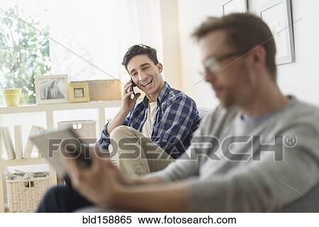Stock Photography - Caucasian gay couple relaxing on sofa. Fotosearch