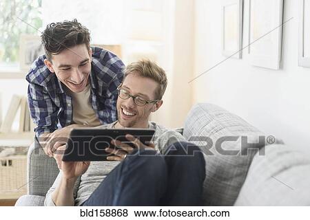 Caucasian gay couple using digital tablet on sofa View Large Photo Image Stock Photo - Caucasian gay couple using digital tablet on sofa. Fotosearch