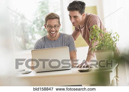 Stock Photo - Caucasian gay couple using laptop. Fotosearch