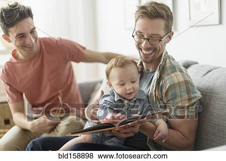 Caucasian gay fathers reading to baby in living room View Large Photo Image Stock Photo - Caucasian gay fathers reading to baby in living room. Fotosearch