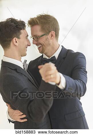 Stock Image - Caucasian gay grooms dancing at wedding. Fotosearch