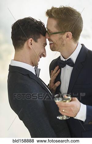 Stock Photo - Caucasian gay grooms drinking champagne at wedding. Fotosearch