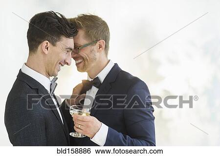 Stock Photograph - Caucasian gay grooms hugging at wedding. Fotosearch