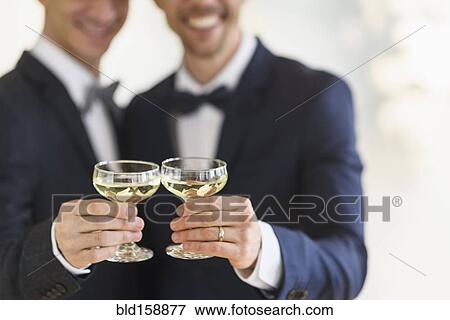 Caucasian gay grooms toasting with champagne at wedding View Large Photo Image Stock Photo - Caucasian gay grooms toasting with champagne at wedding. Fotosearch