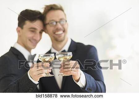Caucasian gay grooms toasting with champagne at wedding View Large Photo Image Stock Photo - Caucasian gay grooms toasting with champagne at wedding. Fotosearch