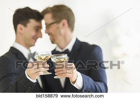 Stock Photo - Caucasian gay grooms toasting with champagne at wedding. Fotosearch