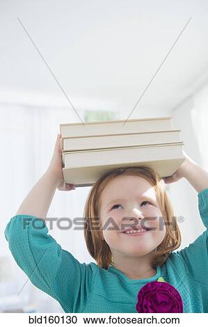 Stock Image - Caucasian girl balancing books on head. Fotosearch